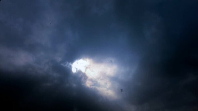 Dramatic sunbeams breaking through dark storm clouds timelapse