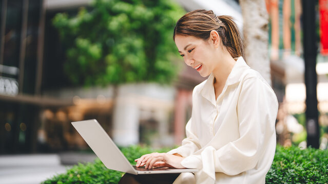 Business travel asian woman using laptop computer sitting at outdoor on day