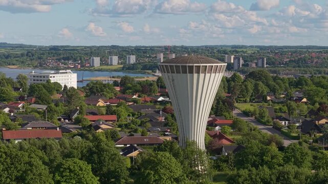 Aerial footage circling the iconic mushroom-shaped water tower on Sjaellandsvej, showcasing Kolding's rooftops, parks, and the picturesque city landscape beneath a bright Danish sky.