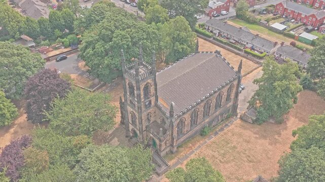 St Mary's Church, rises above Greasbrough, Rotherham, South Yorkshire, England, with its pinnacled sandstone tower and Gothic Revival architecture, drone ascent