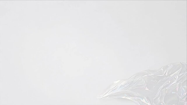 Minimal top view texture background with transparent plastic sheet, crumpled wrinkle detail, delicate folds, soft light, pale surface, and spacious copy space for clean packaging design concepts