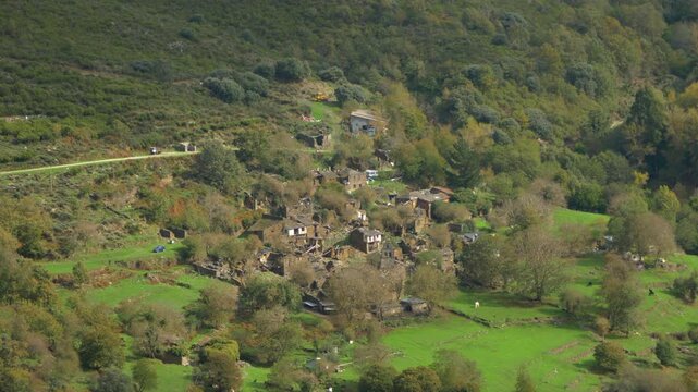 Aerial view over Santoalla do Monte in Galicia, Spain, showing the small mountain settlement, green valley and stone houses surrounded by remote countryside
