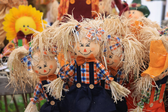 Group of smiling scarecrow dolls decorating for autumn harvest