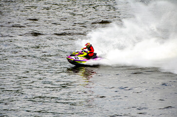 Racer speeding on jet ski carving sharp turn through splashing water. Racing at high speed, adrenaline mood, open water course, extreme watersport action concept © Vivid Impressions LT
