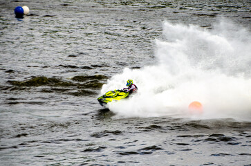 Racer speeding on jet ski carving sharp turn through splashing water. Racing at high speed, adrenaline mood, open water course, extreme watersport action concept © Vivid Impressions LT