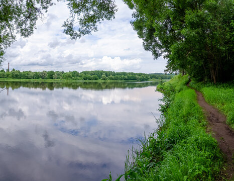 Calm river bend with sandbar birds and forest reflecting cloudy sky. Flowing quietly past sandbar, peaceful mood, riverside forest village, tranquil landscape nature concept