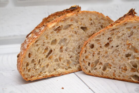 Fresh artisan bread with seeds sliced open to show its soft crumb texture