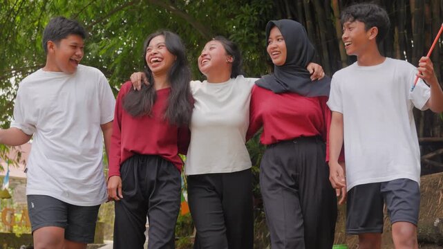 A group of Indonesian people are holding their country flag while smiling and talking to each other. Indonesia Independence Day concept.