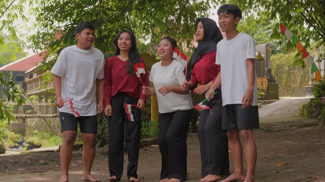 A group of Indonesian people are holding their country flag while jumping in excitement. Indonesia Independence Day concept.