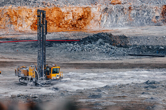 Drilling rig operating in open pit mine with rocky benches for mineral exploration and industrial site background