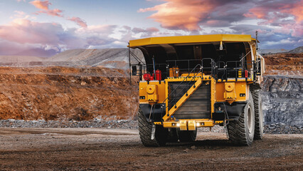 Big yellow mining dump truck in open pit quarry at sunset for industrial background and construction banner design © Parilov