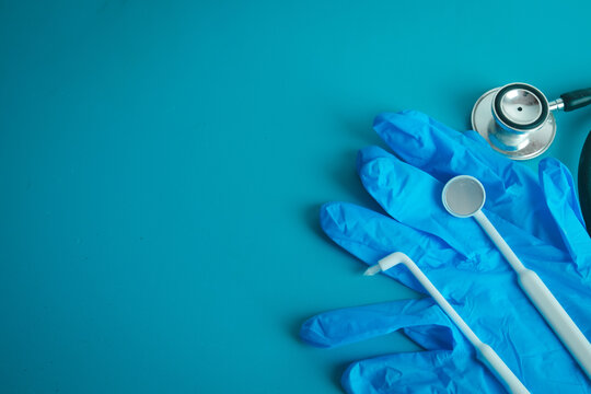Medical and dental instruments including stethoscope, mouth mirror and probe on blue surgical gloves with copy space. Concept of healthcare, dentistry checkup, clinic treatment and health insurance.