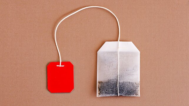 Tea bag and loose tea leaves on a simple brown background for beverage preparation concept