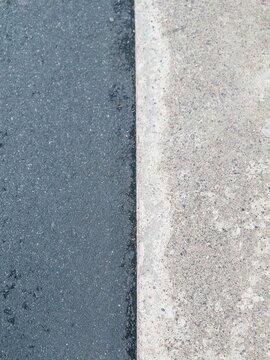 Concrete curb and dark asphalt road surface texture boundary