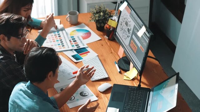 Top view of manager writing idea while team standing and giving comment. Professional designer design logo while looking at color palette and writing idea down in paper with color marker. Symposium.