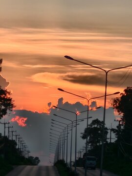 A dramatic twilight sky painted in brilliant shades of orange and gold as the sun sets behind dark, silhouetted clouds.