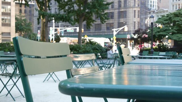 Fifth 5 avenue and Broadway street crossroad, Manhattan Midtown, New York City, United States. Defocused people pedestrians, chairs and tables for picnic in Madison Square Park, Flatiron District .