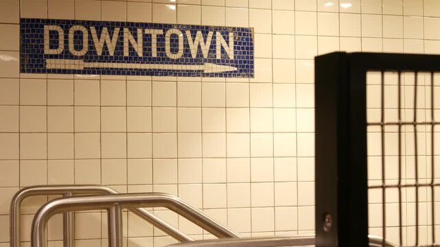 New York City Manhattan Midtown underground subway, Downtown metro direction, United States railway. Public metropolitan transport in USA, american railroad navigation. Sign on wall, tiles and arrow.