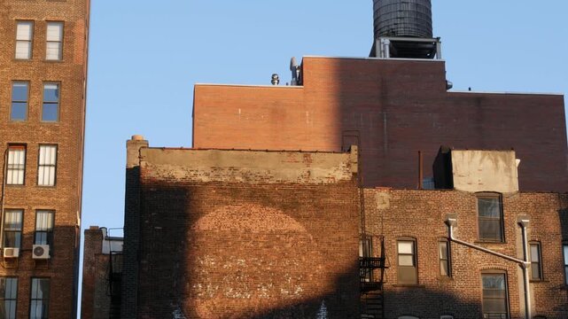 New York City Midtown urban red brick building architecture, Manhattan rooftop, United States of America. Water tower on roof. Classic water tanks. Hells Kitchen, Chelsea, Port Authority area. Sunset.