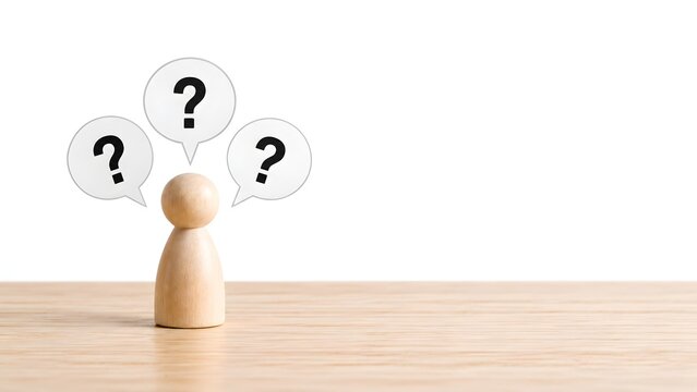 Wooden peg figure with three question marks in speech bubbles above its head representing confusion or uncertainty