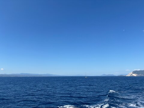 The indescribable beauty and power of the deep blue Aegean Sea, set against coastal hills barely visible on the horizon.