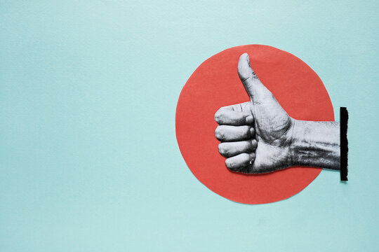 Hand showing thumbs up gesture on paper cutout red circle background with copy space