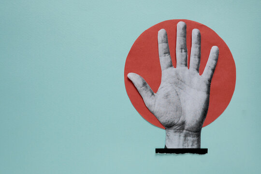 Open hand showing stop gesture on paper cutout red circle background with copy space