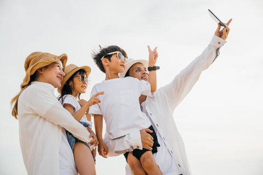 Summer bliss on the beach as a happy family captures memories through a cheerful selfie near the sea. Laughter joy and togetherness shine in this delightful family portrait. Family on beach vacation