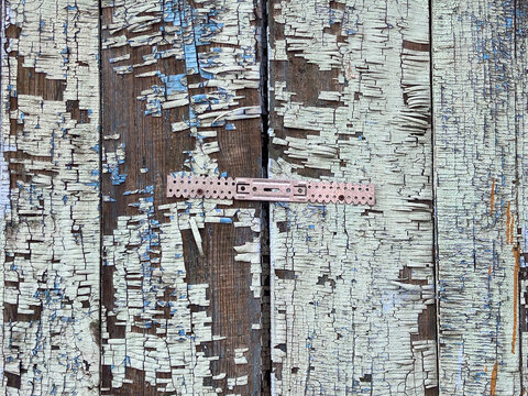 Weathered wooden planks with heavily cracked and peeling white paint reveal dark grain and splintered texture