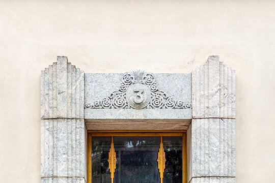 Art Deco building facade featuring carved granite ornament with the house number 3, showcasing architectural detail and historical design in Helsinki, Finland