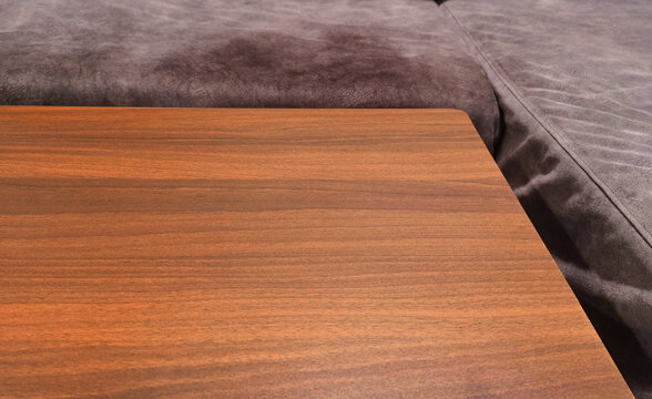 Wooden table surface foreground with comfortable cozy couch in background.