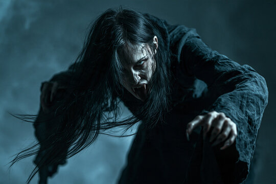 Nosferatu Vampire Woman Attacking with Long Black Hair and Sharp Fangs in Chilling Blue Halloween Darkness