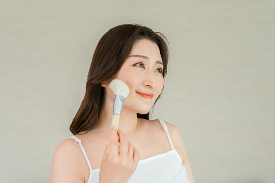Woman Applying Makeup to Her Cheek with a Cosmetic Brush in a Beauty and Skincare Concept