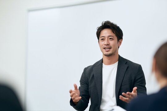 会議室でプレゼンテーションを行う日本人ビジネスマン