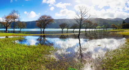 Obraz premium Azores - Reflection in lake Azul with sun and green grass in water, Sete Cidades, San Miguel, Portugal