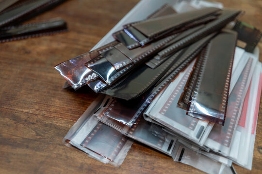 Photographic negatives are scattered on the wooden table. Digitization of old film. Analog photography and the concept of archive preservation.
