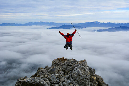 Mountaineer Celebrating Success Above the Clouds on a Rocky Mountain Summit
