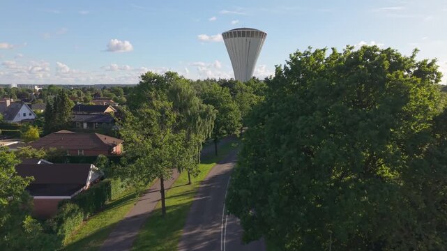 Aerial footage showcasing the peaceful suburban landscape of Kolding before revealing the city's distinctive mushroom-shaped water tower rising above trees and homes.