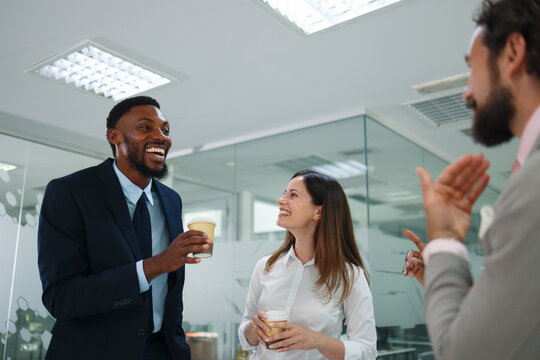 Diverse business professionals enjoying a coffee break, communicating and collaborating in a modern office, sharing ideas and building positive connections with smiling faces