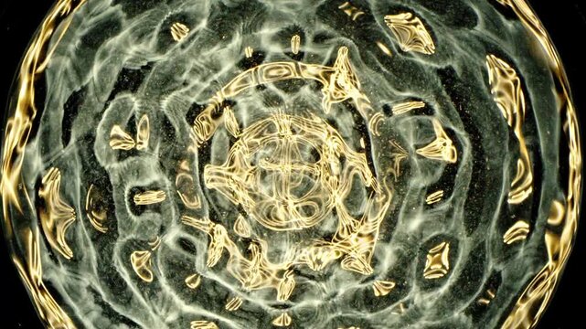 Cymatics wave patterns created by sound frequencies in liquid, forming complex symmetrical golden structures and concentric ripples on a dark background.