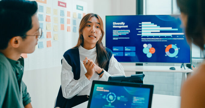 Group of Asian businesspeople work together discuss plan idea with investment data profit sale statistics in business meeting in office. Financial generation z team brainstorm on e-Commerce project.