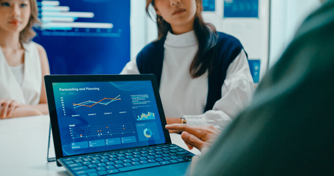 Closeup group Asian businesspeople work together discuss plan idea with investment profit sale statistics in business meeting in office. Financial generation z team brainstorm on e-Commerce project.