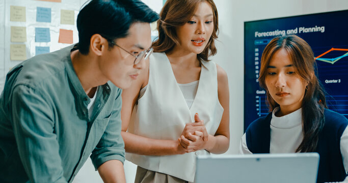 Group of Asian businesspeople work together discuss plan idea with investment data profit sale statistics in business meeting in office. Financial generation z team brainstorm on e-Commerce project.