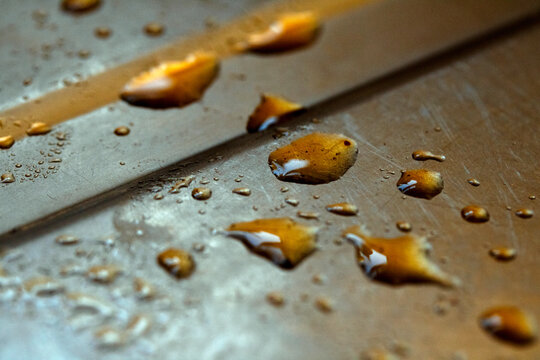 Drops of cooking fat oil liquid spilt on a stainless steel kitchen sink messy food preparation