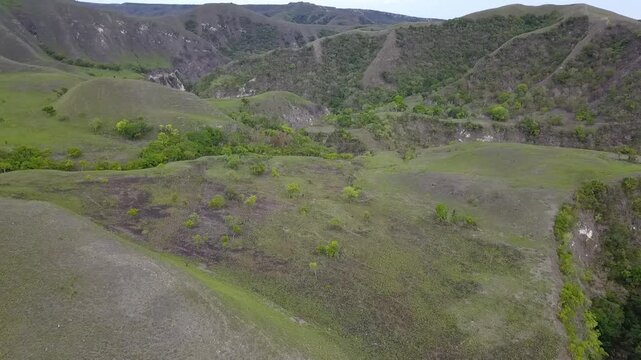 Scenic rolling savanna hills surrounding Tanggedu waterfall landscape in East Sumba