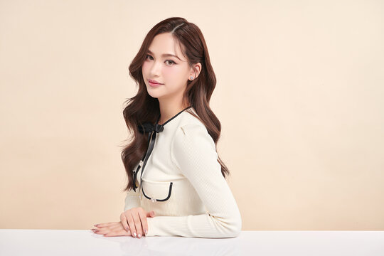 A beautiful young Asian woman with clean, fresh skin against a beige background. Skincare, facial treatment, cosmetology, beauty, and spa. An elegant portrait of an Asian woman.