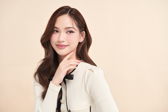 A beautiful young Asian woman with clean, fresh skin against a beige background. Skincare, facial treatment, cosmetology, beauty, and spa. An elegant portrait of an Asian woman.