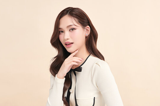 A beautiful young Asian woman with clean, fresh skin against a beige background. Skincare, facial treatment, cosmetology, beauty, and spa. An elegant portrait of an Asian woman.