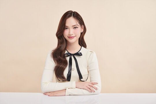 A beautiful young Asian woman with clean, fresh skin against a beige background. Skincare, facial treatment, cosmetology, beauty, and spa. An elegant portrait of an Asian woman.