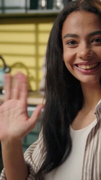 Hispanic young woman working online on laptop at kitchen home smiling and waving hello happy Latina student freelancer businesswoman studying shopping food delivery remote work greeting looking camera